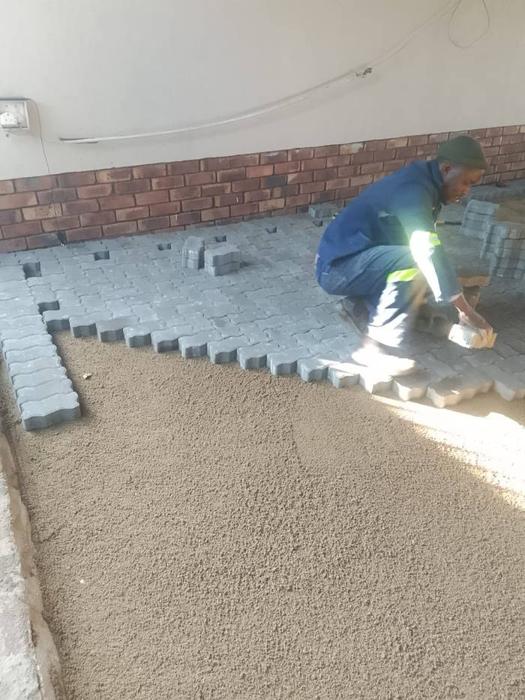 Worker laying paving bricks by hand